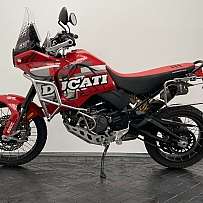 Ein rotes Ducati DesertX Motorrad auf einem schwarzen Boden.