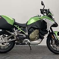 Ein grünes Ducati-Motorrad mit Gepäckträger auf einem grauen Boden.