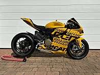 Ein gelbes Ducati Motorrad mit auffälligen Aufklebern auf einem Pflastersteinboden.