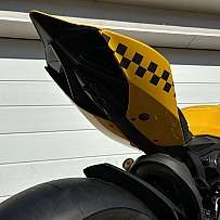 Detailaufnahme des Hecks eines gelben Motorrads mit Schachbrettmuster.