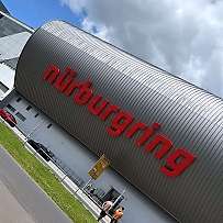 Das Gebäude des Nürburgrings mit Besuchern und blauem Himmel.