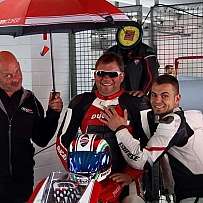 A group of people celebrating with a Ducati motorcycle and umbrella.