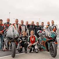 Eine Gruppe von Motorradfahrern posiert mit ihren Motorrädern auf der Rennstrecke.