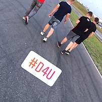 Vier Personen gehen auf einer Rennstrecke in der Motorsport Arena.
