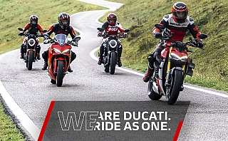 Vier Ducati Motorräder fahren auf einer kurvenreichen Straße.