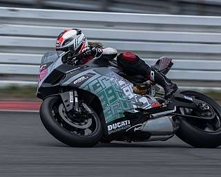 Ein Motorradfahrer kurvt mit hoher Geschwindigkeit auf einer Rennstrecke.