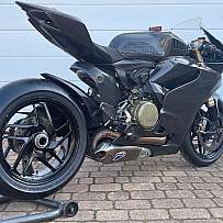 Ein schwarzes Ducati Rennmotorrad auf einem Ständer, seitliche Ansicht.