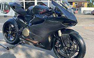 Ein schwarzes Ducati Rennmotorrad mit Carbon-Verkleidung und sportlichem Design.