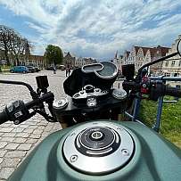 Blick auf das Motorradlenkrad mit Stadtansicht im Hintergrund.