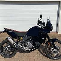 Ein schwarzes Adventure-Motorrad steht vor einer Garagentür.