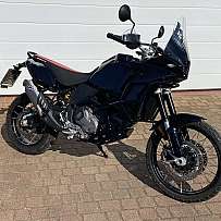Ein schwarzes Motorrad steht auf einem gepflasterten Weg.