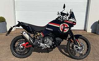 Ein Ducati DesertX Motorrad steht vor einer Garage.