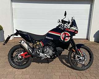 Ein Ducati DesertX Motorrad steht vor einer Garage.