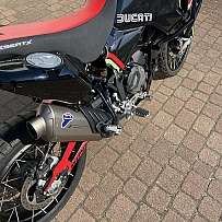 Detailaufnahme eines Ducati DesertX Motorrads auf einem Pflastersteinboden.