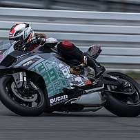 Ein Motorradfahrer in voller Montur fährt schnell auf einer Rennstrecke.