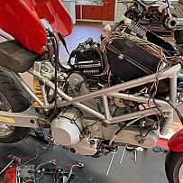 Ein Motorrad mit sichtbarem Motor und Kabeln in einer Werkstatt.
