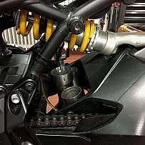 Detailaufnahme eines Motorrad-Federungssystems mit gelben Federn und Rohren.
