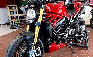 Ein rotes Ducati-Motorrad in einer Werkstatt mit Werkzeugen im Hintergrund.