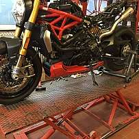 Ein unvollständiges Motorrad auf einer Hebebühne in einer Werkstatt.