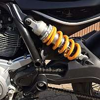 Detailaufnahme eines Motorrad-Federungssystems mit orangefarbener Feder.