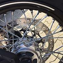 Detailaufnahme einer Motorradfelge mit Speichen und Bremsscheibe.