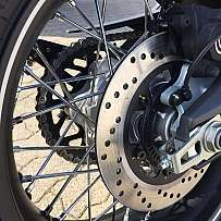 Detailaufnahme der Hinterradbremse und Speichen eines Motorrads.