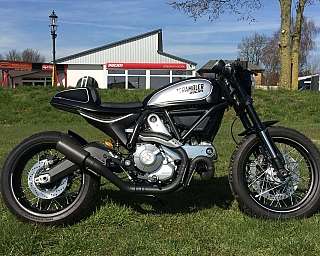 Ein Ducati Scrambler Motorrad auf einer grünen Wiese.