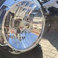 Nahaufnahme eines glänzenden Motorrad-Scheinwerfers mit reflektierendem Glas.