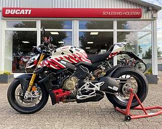 Ein Ducati Motorrad steht vor einem Verkaufsraum mit Schaufenstern.