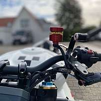 Nahaufnahme eines Motorradlenkers mit rotem Zubehör und Kabeln.