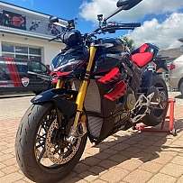 Ein schwarzes und rotes Motorrad steht auf einem Parkplatz.