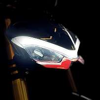 Nahaufnahme eines Motorrad-Scheinwerfers in dunkler Umgebung.