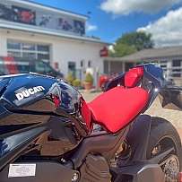 Nahaufnahme eines Ducati Motorrads mit rotem Sitz und blauem Lack.
