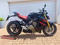 Ein schwarzes Ducati Motorrad mit roten Akzenten auf einem Pflastersteinboden.