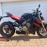 Ein schwarzes Ducati Motorrad mit roten Akzenten auf einem Pflastersteingelände.