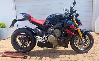 Ein schwarzes Ducati Motorrad mit roten Akzenten auf einem Pflastersteinboden.