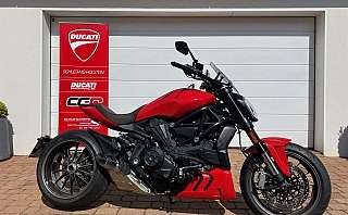 Ein rotes Ducati Motorrad steht vor einer weißen Garage.