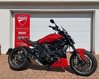 Ein rotes Ducati-Motorrad vor einer weißen Garage.