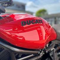 Nahaufnahme eines roten Ducati-Motorradtanks mit glänzender Oberfläche.