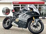 Ein schnittiges Ducati-Sportmotorrad, das vor einem Autohaus geparkt ist.