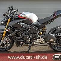 Ein sportliches Ducati Motorrad steht vor einer grauen Wand.