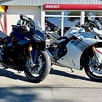 Zwei Ducati Motorräder, eines schwarz und eines weiß, vor einem Geschäft.