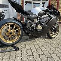 Seitenansicht eines Ducati Motorrads mit goldenen Felgen und Carbon-Elementen.