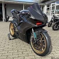 Ein sportliches Motorrad mit Carbon-Verkleidung und goldenen Felgen.