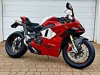 Ein rotes Ducati Rennmotorrad steht auf einem gepflasterten Boden.