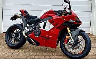 Ein rotes Ducati Rennmotorrad steht auf einem gepflasterten Boden.
