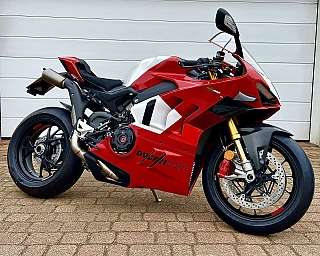 Eine rote Ducati Sportmaschine steht auf einem gepflasterten Boden.