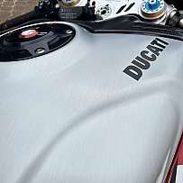 Detailaufnahme des Tanks eines Ducati Motorrads mit glänzender Oberfläche.