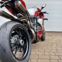 Detailansicht eines roten Sportmotorrads mit breitem Hinterrad.