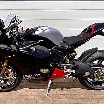 A sleek Ducati Panigale V4 motorcycle parked against a white wall.